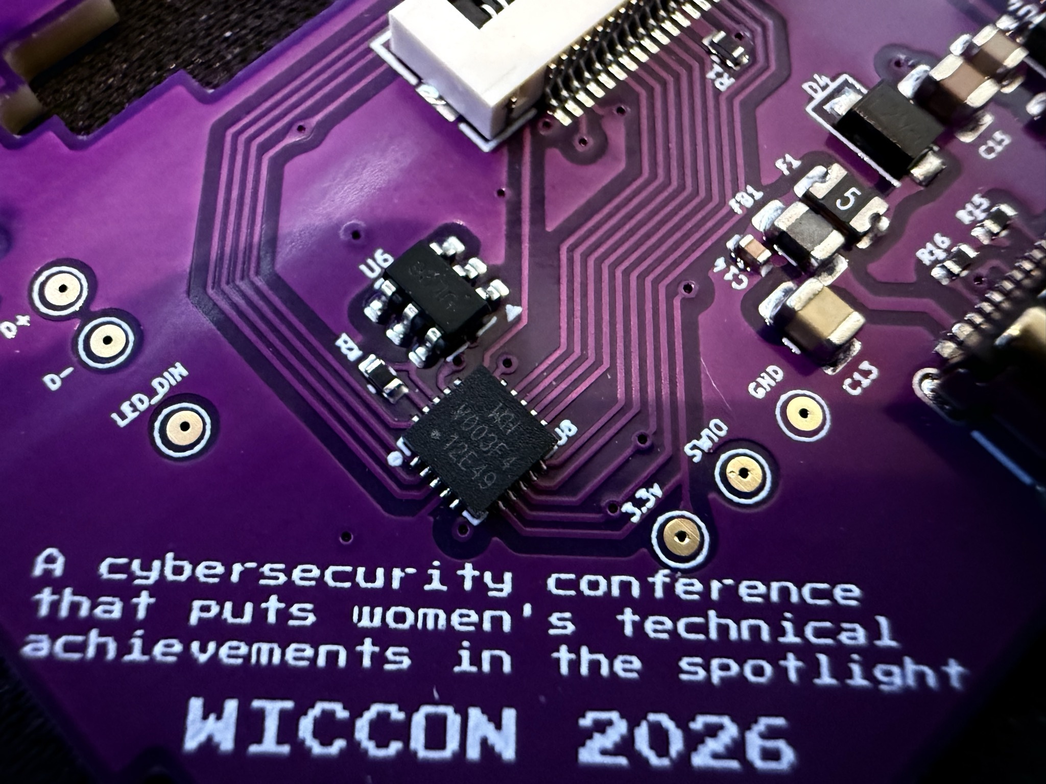 Close-up of CH32V microcontroller and silkscreen mission statement on WICCON 2026 badge